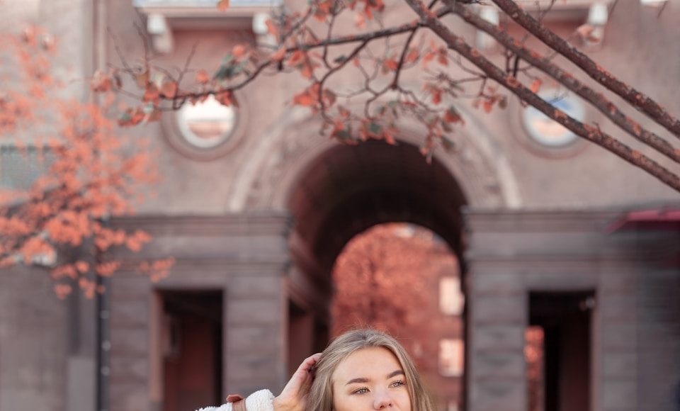 a woman standing in front of a building with her hands on her head