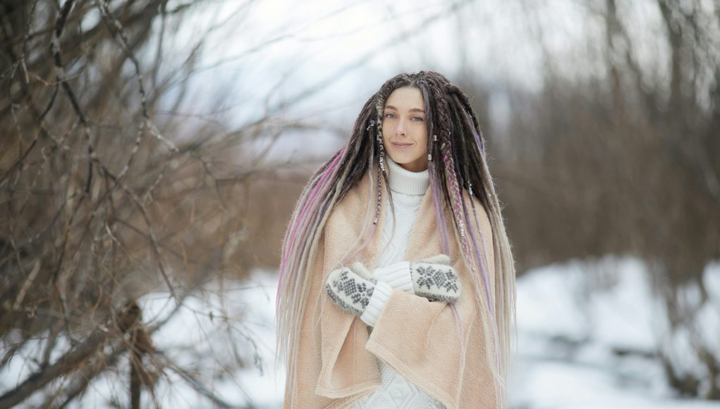 woman in pink long sleeve shirt and white skirt standing on snow covered ground during daytime