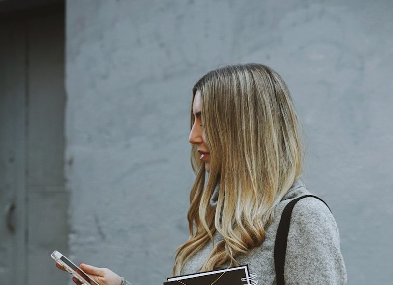 woman holding denim jacket and phone