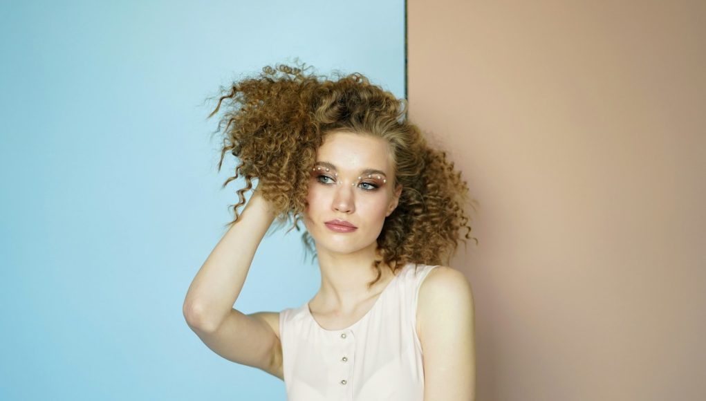 woman leaning on wall holding her hair