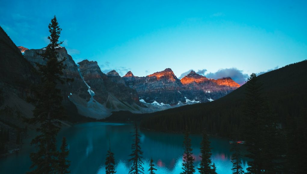 Mountains reflect in a serene, turquoise lake.