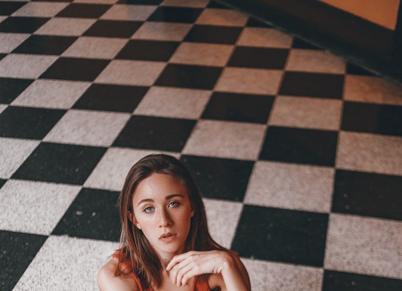 woman in brown tank top and blue jeans sitting on floor