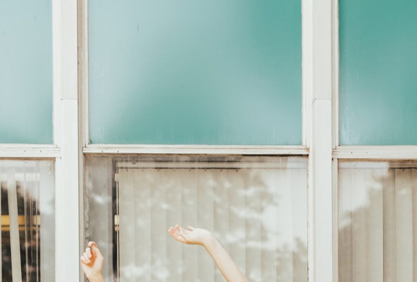 a woman standing in front of a window with her arms in the air